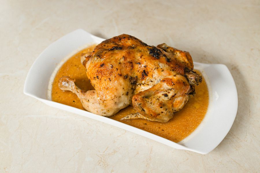 Ayam panggang penuh dihidang di atas pinggan putih